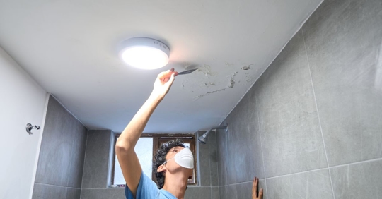 person with mask looking at mold damage on ceiling